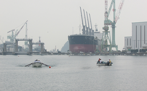 本社工場をバックに力漕するBチーム